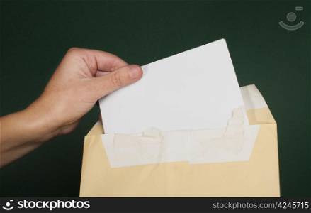 Hand that open a letter from brown envelope. Dark green background