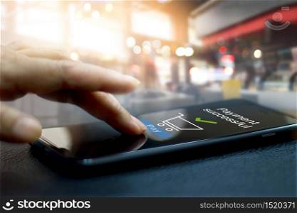 Hand touching mobile screen of a Payment successful message on shopping mall background