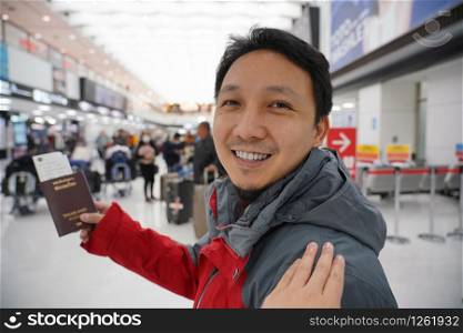 Hand touching on the asian shoulder for greeting friend at the airport when waiting flight on board, hand holding passport with big baggage, traveler and friendly concept