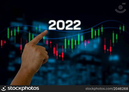 hand touching screen digital virtual futuristic interface 2022 New year candlestick graph chart auto trade, business finance investment stock exchange market concept background.