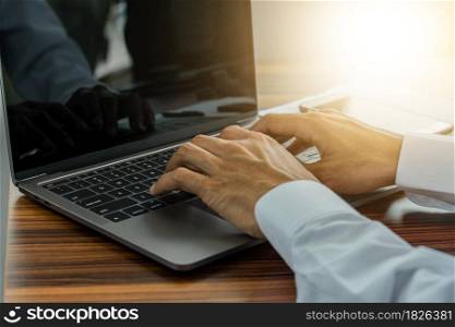 Hand typing computer in office workspace