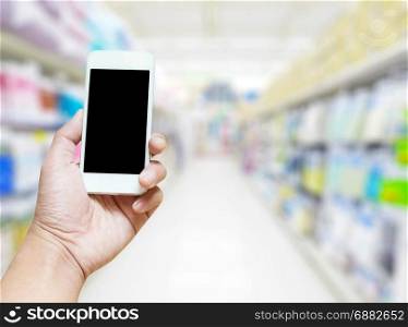 hand use smart phone on blurred photo of supermarket shelf background clipping path screen include