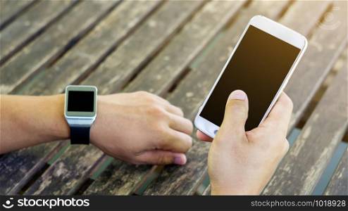 hand using a smartphone and a smartwatch.