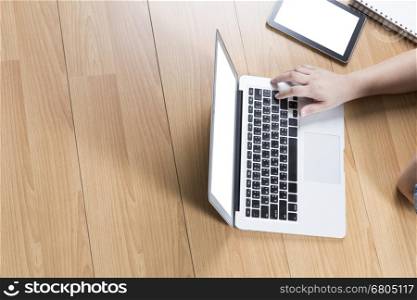hand using computer notebook with tablet on wooden office desk