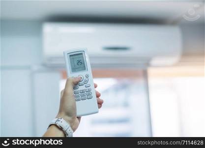 hand using remote controller for adjust Air conditioner inside the room of office or house