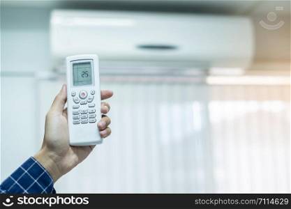 hand using remote controller for adjust Air conditioner inside the room of office or house