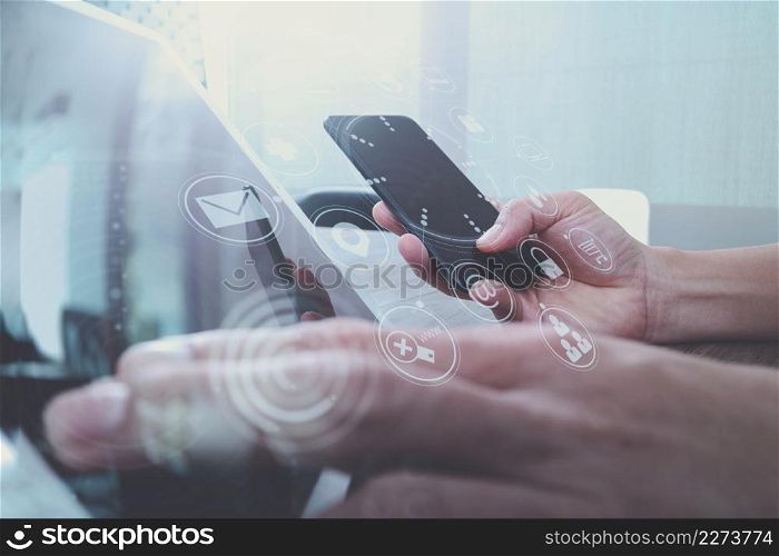 hand using smart phone,mobile payments online shopping,omni channel,digital tablet docking keyboard computer in modern office on wooden desk,virtual interface icons screen