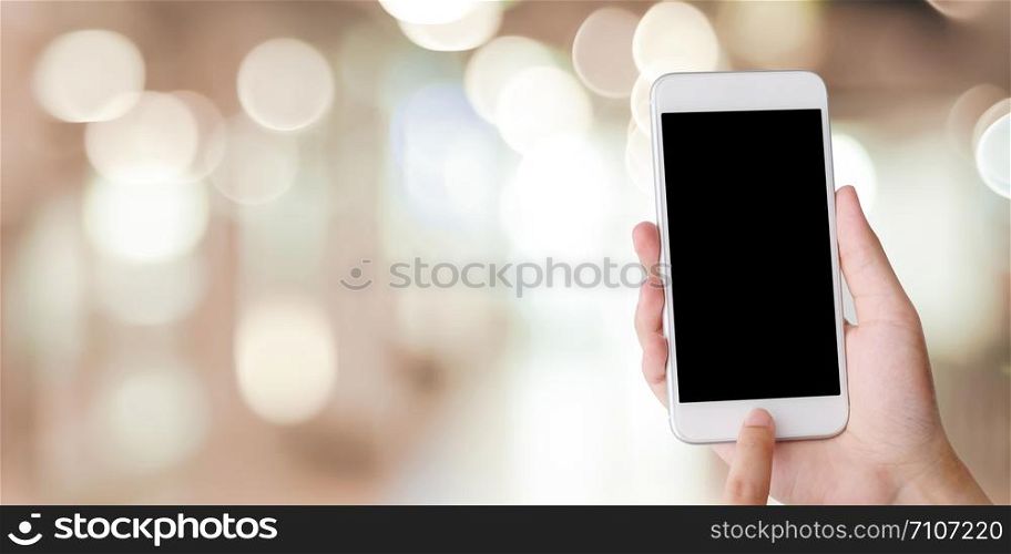 Hand using smart phone with blank screen over blur bokeh light background, business and technology, internet of things concept