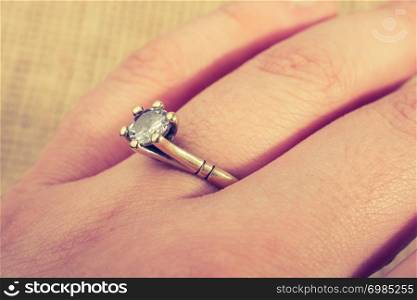 Hand wearing a fake diamond ring on a textured background