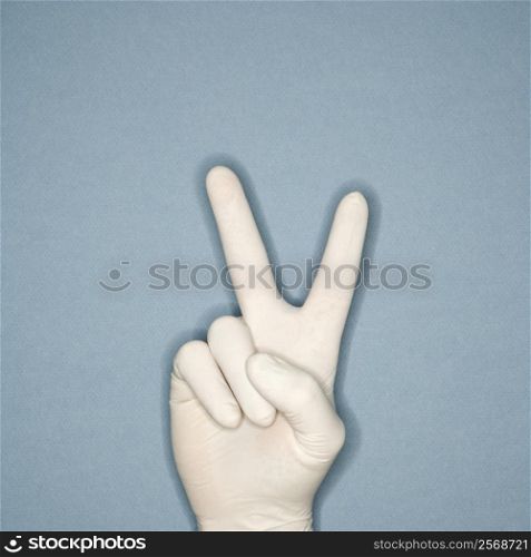 Hand wearing white rubber glove making a gesture meaning peace.