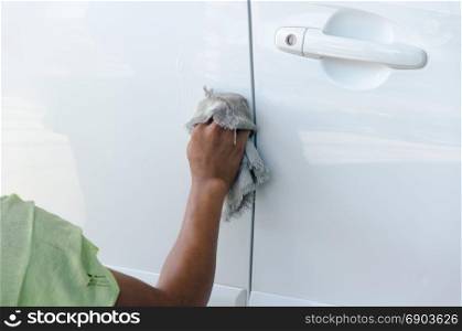 hand wiping water on white car