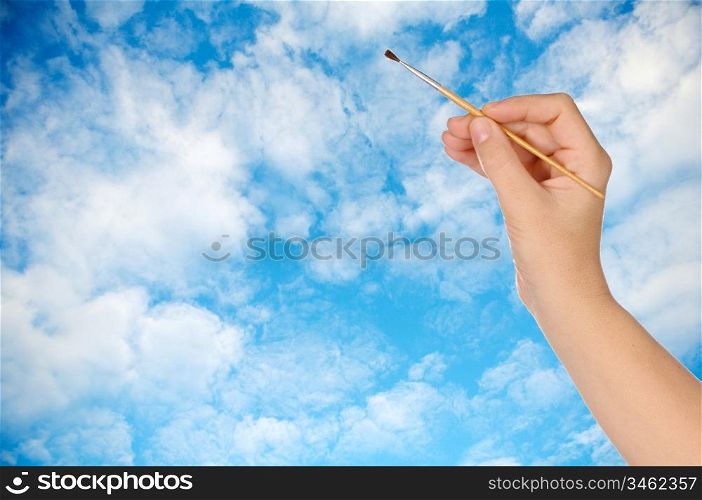 Hand with a brush drawing a sky