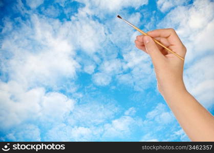 Hand with a brush drawing a sky