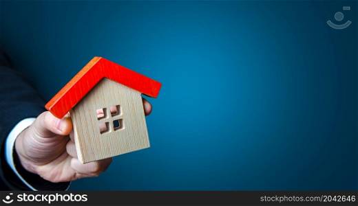Hand with a house on a blue background. Buying and selling housing. Search for options. Buy, rent. Place for text, copy space. Design and construction. Property appraisal. Affordable mortgage loan.