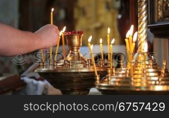 hand with a lit candle in the church