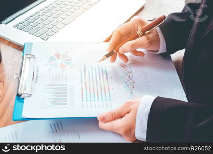 hand with a pen writing on the business paper. Report chart