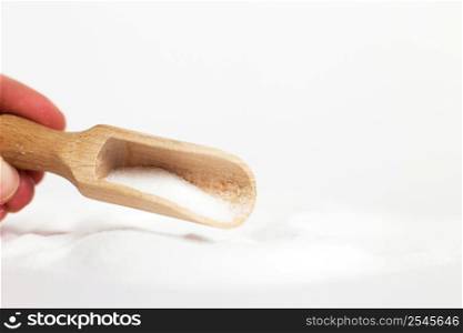 hand with a wooden spoon of salt grain on a white background. hand with a wooden spoon of salt grain on white background