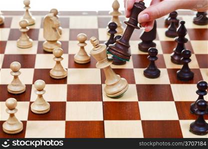 hand with black king pushes white king on chessboard in chess game