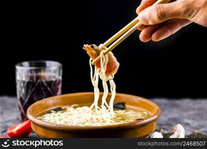 hand with chopsticks holding shrimp noodles