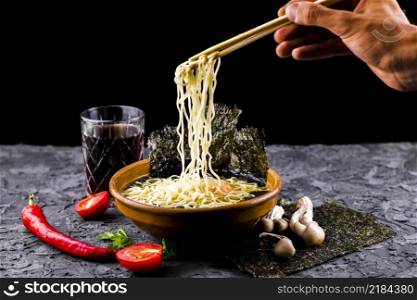 hand with chopsticks noodles soup