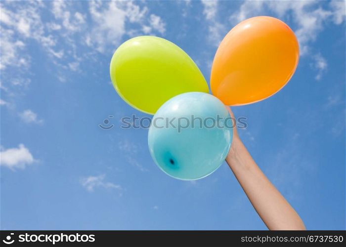 hand with color balloons on sky background