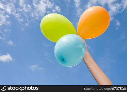 hand with color balloons on sky background
