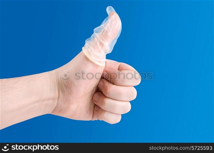 Hand with condom on finger on blue
