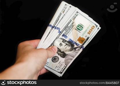 Hand with dollar bills on a black background.. Hand with dollar bills on a black background