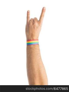 hand with gay pride rainbow wristband shows rock. lgbt, same-sex relationships and homosexual concept - close up of male hand wearing gay pride awareness wristband showing rock or hand-horns sign