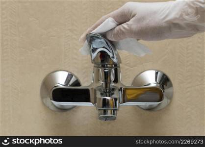 hand with glove disinfecting faucet