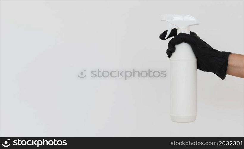 hand with glove holding disinfectant bottle with copy space