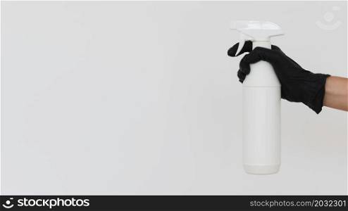 hand with glove holding disinfectant bottle with copy space