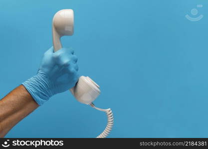 hand with glove holding telephone receiver with copy space