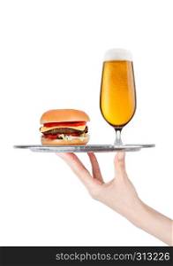 Hand with glove holds tray with fresh beef burger and beer glass with vegetables and sauce on white background