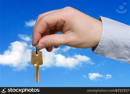 hand with key on blue sky background