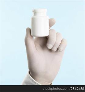 hand with latex glove holding medicine bottle 2