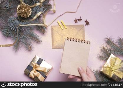 hand with notebook near present boxes fir twigs envelope ribbon
