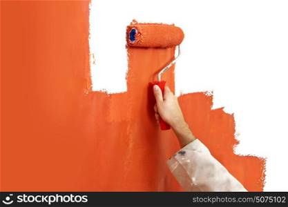 Hand with paint roller covered in bright orange, painting over a white wall