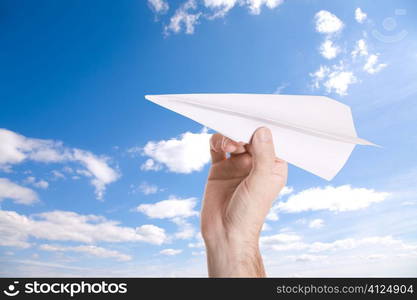 hand with paper airplane on blue sky background