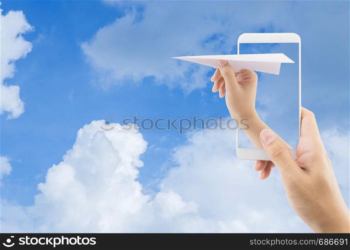 Hand with paper plane with mobile phone against blue sky sending email, communication concept.