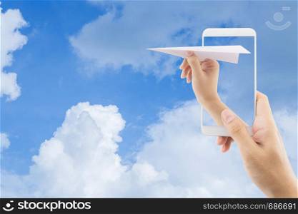 Hand with paper plane with mobile phone against blue sky sending email, communication concept.