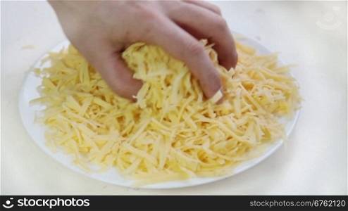 Hand with pieces of grated cheese for pizza