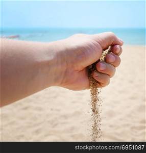 Hand with sand against tropical sea