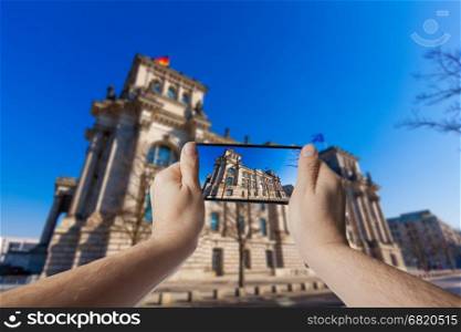 Hand with smartphone taken pictures of The Reichstag building in Berlin, Germany