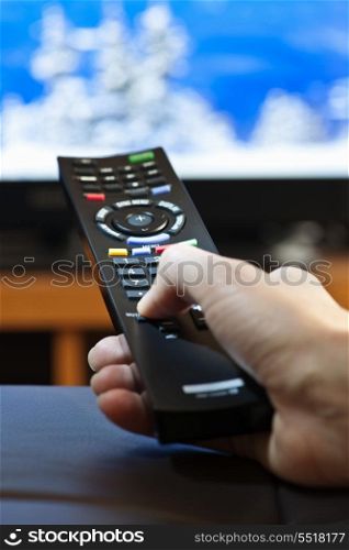 Hand with television remote control. Hand holding television remote control pressing buttons