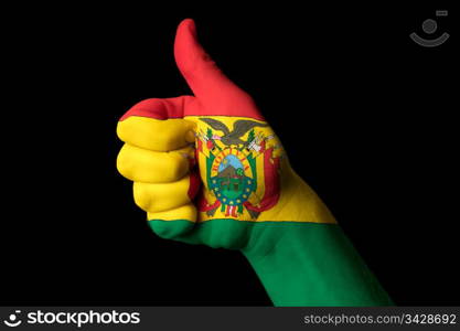 Hand with thumb up gesture in colored bolivia national flag as symbol of excellence, achievement, good, - for tourism and touristic advertising, positive political, cultural, social management of country