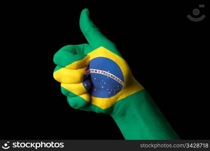 Hand with thumb up gesture in colored brazil national flag as symbol of excellence, achievement, good, - for tourism and touristic advertising, positive political, cultural, social management of country