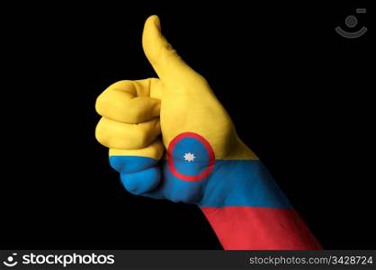 Hand with thumb up gesture in colored colombia national flag as symbol of excellence, achievement, good, - for tourism and touristic advertising, positive political, cultural, social management of country