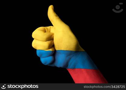Hand with thumb up gesture in colored colombia national flag as symbol of excellence, achievement, good, - for tourism and touristic advertising, positive political, cultural, social management of country