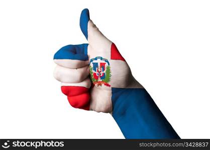 Hand with thumb up gesture in colored dominican national flag as symbol of excellence, achievement, good, - for tourism and touristic advertising, positive political, cultural, social management of country